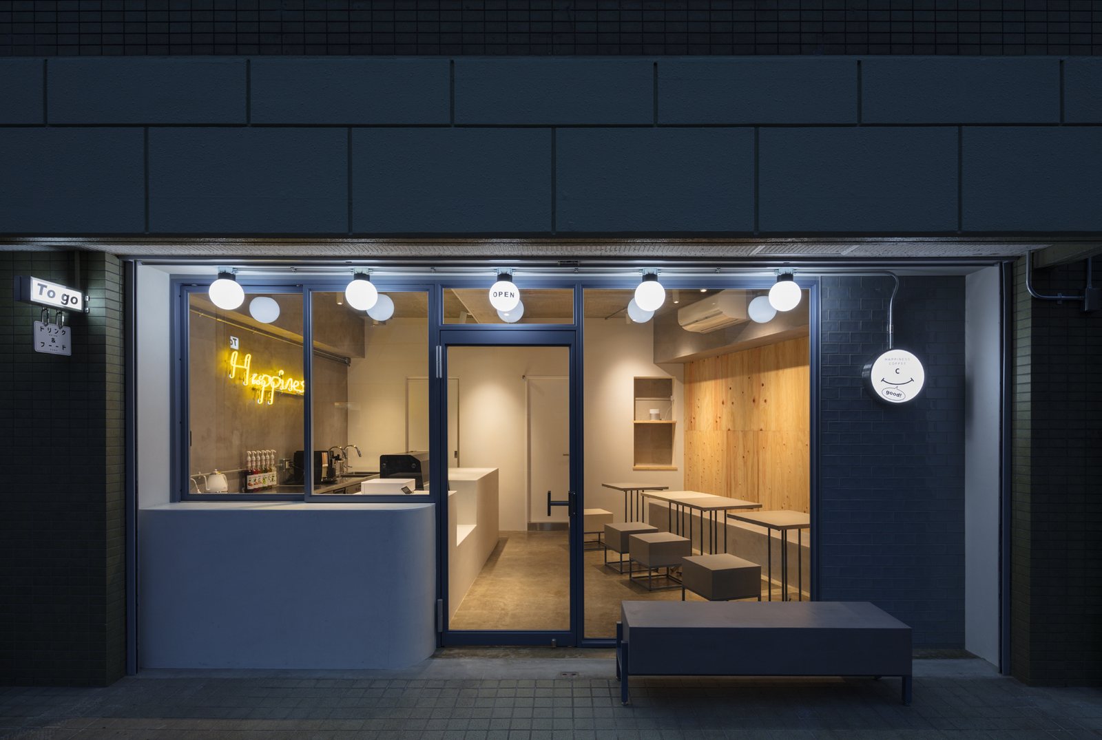 夜のカフェ店舗の外観。ネイビーの外壁に球体照明とネオンサイン